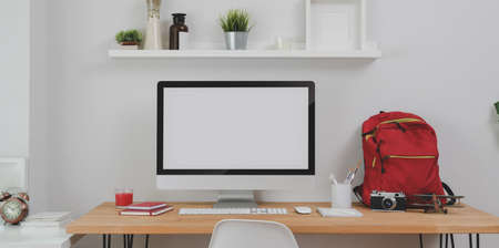 Modern workplace with desktop computer and office supplies with red backpack on wooden tableの写真素材