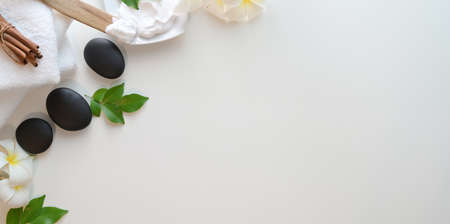 Top view of black stones and towels for massages on white background. Spa therapy concept