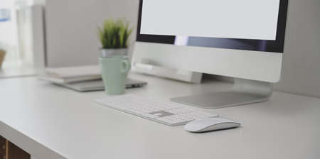 Close-up view of modern workplace with desktop computer and office supplies on white tableの写真素材