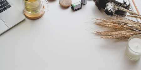 Modern workplace with vintage camera and office supplies with decorations on white table background, top view with copy spaceの写真素材