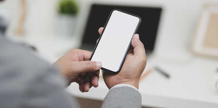 Close-up view of businessman holding blank screen smartphone in his modern office room.の写真素材