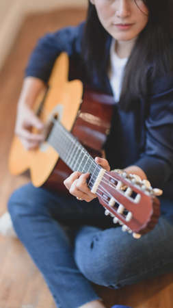 Beautiful woman playing acoustic guitar in comfortable room.の写真素材