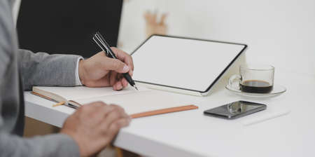 Close-up view of businessman writing his idea on notebook in his modern office roomの写真素材