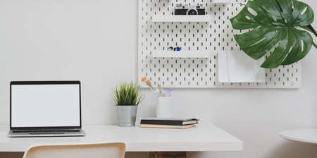 Open blank screen laptop computer with copy space and office decorations in minimal white office roomの写真素材