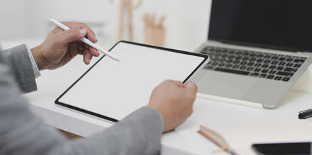 Close-up view of businessman writing his plan on blank screen tablet in his modern office roomの写真素材