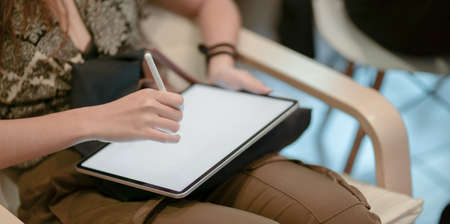 Close-up view of young professional designer working on her project while drawing on blank screen tabletの写真素材