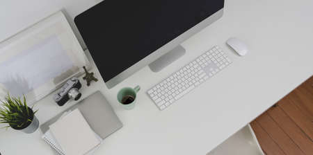 Top view of desktop computer and office supplies with copy space in minimal white office roomの写真素材