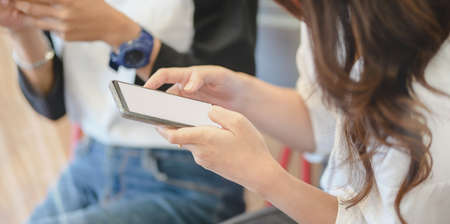 Close-up view of young female looking at blank screen smartphone in comfortable roomの写真素材