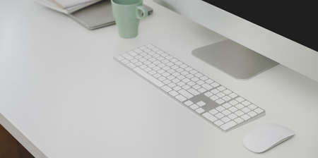 Cropped shot of desktop computer and office supplies with copy space in minimal office room.の写真素材