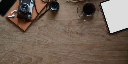 Overhead shot of rustic wooden workplace with blank screen tablet with vintage camera and copy spaceの写真素材