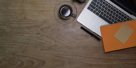 Top view of workplace with laptop computer with coffee cup and notebook on wooden table backgroundの写真素材