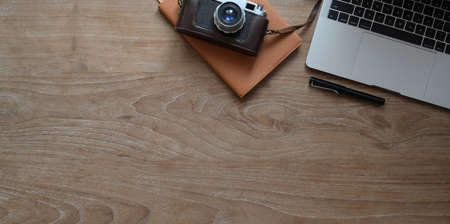 Overhead shot of modern rustic workplace with laptop computer, camera and office supplies with copy spaceの写真素材