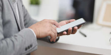 Close-up view of businessman holding blank screen smartphone in his modern office room