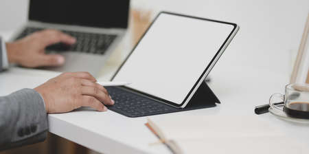 Close-up view of professional businessman typing on laptop and tablet in modern office roomの写真素材
