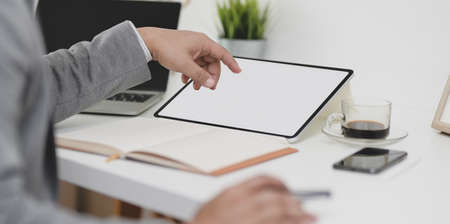 Cropped view of professional businessman working on his project with blank screen tablet in modern office roomの写真素材