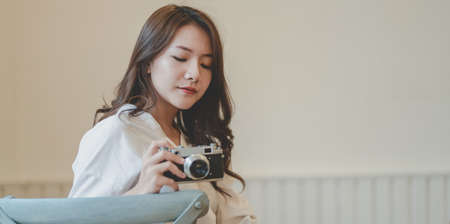 Portrait of beautiful professional photographer holding camera in comfortable roomの写真素材