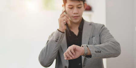 Professional businessman speaking on the phone while checking the time.の写真素材