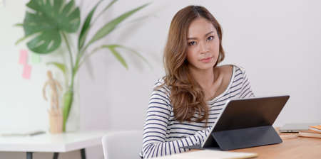 Professional young designer editing her project on tablet and looking at the camera.の写真素材