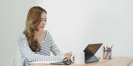 Young professional graphic designer working on her project with tablet in comfortable workplaceの写真素材