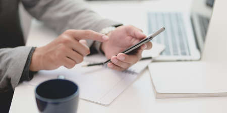 Close-up view of businessman holding blank screen smartphone in his modern office room