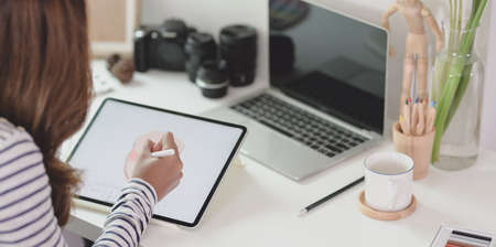 Close-up view of young designer editing her project on tablet in her comfortable workplaceの写真素材