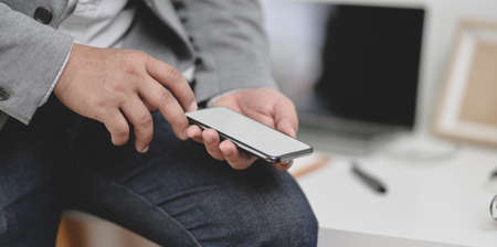 Close-up view of businessman holding blank screen smartphone in his modern office roomの写真素材