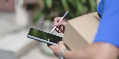 Close-up view of professional delivery man working with parcel box while checking customer order on...