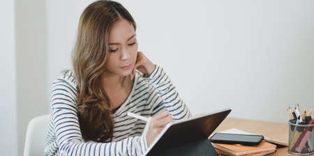 Professional young designer editing her project on tablet in her comfortable workplaceの写真素材