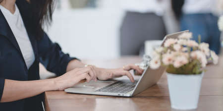 Close-up view of professional female freelancer working on her project while typing on laptop...