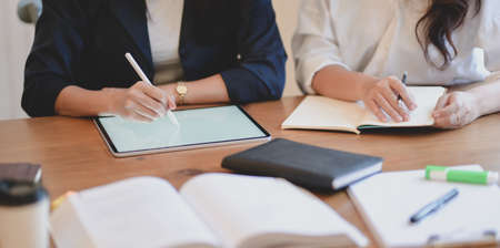 Cropped shot of female freelancers working on their project with tablet in modern workplaceの写真素材