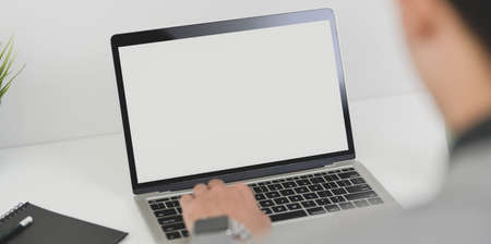 Young professional businessman working on his current project while typing on blank screen laptop computerの写真素材