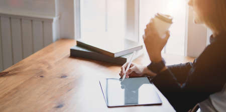 Beautiful professional businesswoman drinking a cup of coffee while working on her project in modern office roomの写真素材