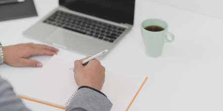 Young professional businessman working on his current marketing plan while writing on blank notebook.の写真素材