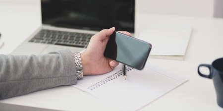 Cropped shot of young professional businessman looking for new ideas on his smartphone.の写真素材