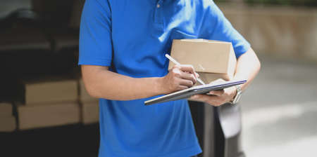 Close-up view of young delivery man checking the products to customer while standing right next to his car.の写真素材