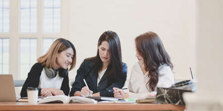 Young professional startup team discussing the project together while using laptop computer in workplaceの写真素材