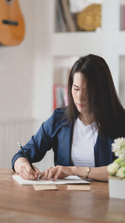 Professional businesswoman working on her projects while writing her idea on notebookの写真素材