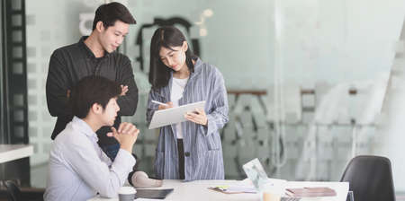 Young female businesswoman explaining her strategy to team members while using tabletの写真素材