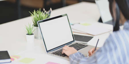 Close-up view of young businesswoman typing on laptop computer while working on her conceptの写真素材