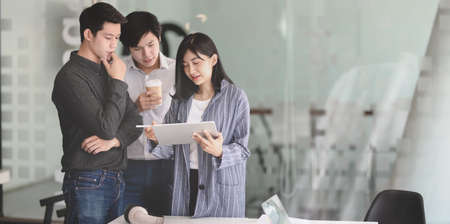Young female businesswoman showing her strategy to team members with tablet in the meeting roomの写真素材
