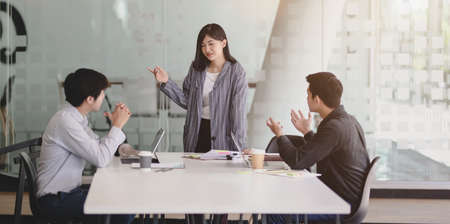 Young female businesswoman showing her strategy to team members with tablet in the meeting roomの写真素材