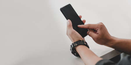 Close-up of young businessman touching his smartphone in the office room.の写真素材