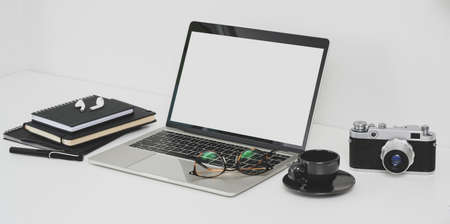 Professional photographer workplace with open blank screen laptop, camera and office supplies on white tableの写真素材