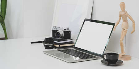 Minimal photographer workplace with open blank screen laptop and office suppliesの写真素材