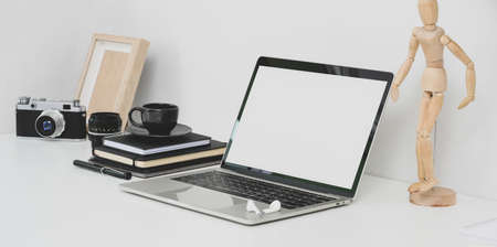 Professional photographer workplace with open blank screen laptop, camera and office supplies on white tableの写真素材