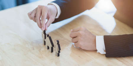 Family care and protection insurance concept : Young businessman display house and family models on the deskの写真素材