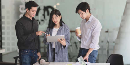 Young professional startup group brainstorming their project together while using tablet in the meeting roomの写真素材