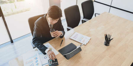Young professional accountant preparing financial reports with charts and graphs while drinking a cup of coffeeの写真素材