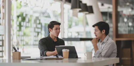 Two professional businessmen discussing their progress of their current project while using tabletの写真素材