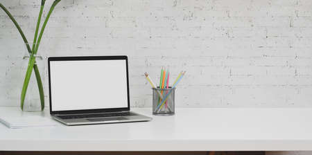 Minimal designer workplace with laptop computer and office supplies on white table with copy spaceの写真素材